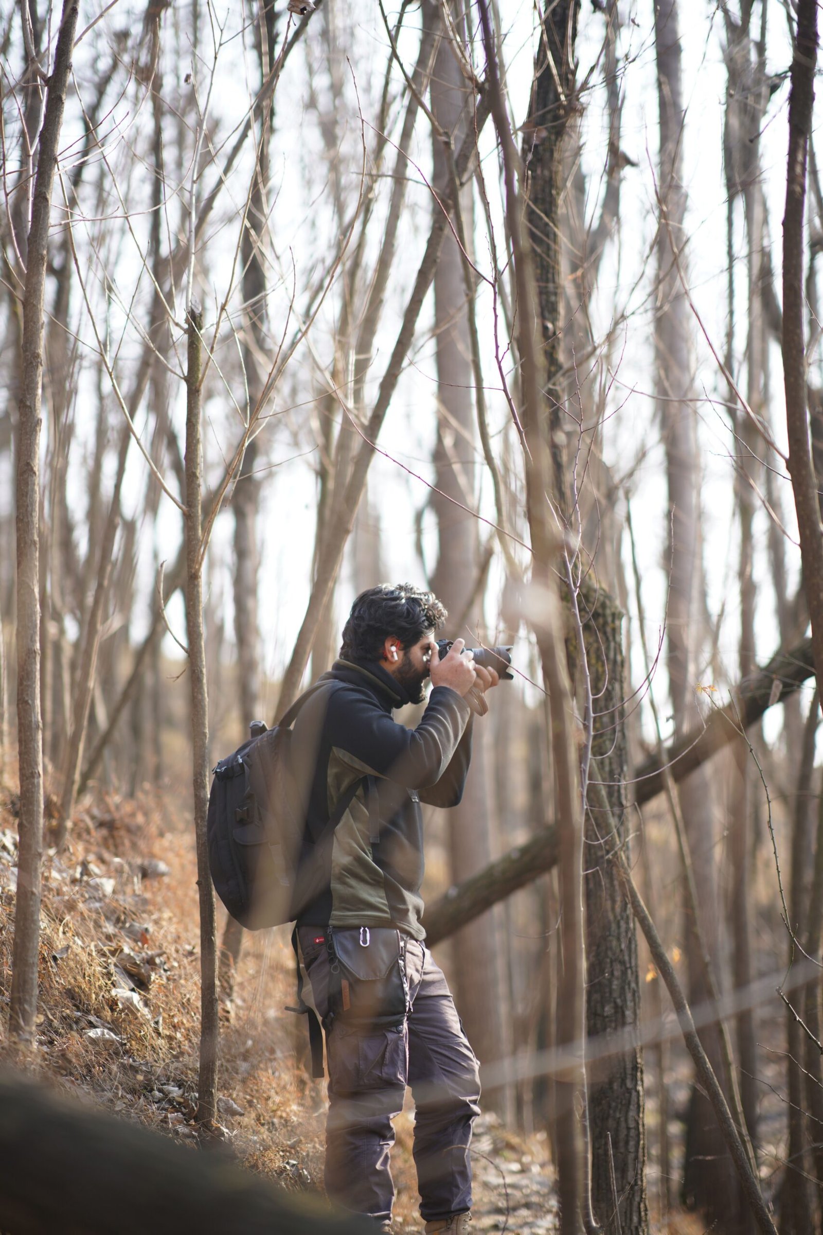 Man with a camera backpack captures the serene beauty of a forest landscape.